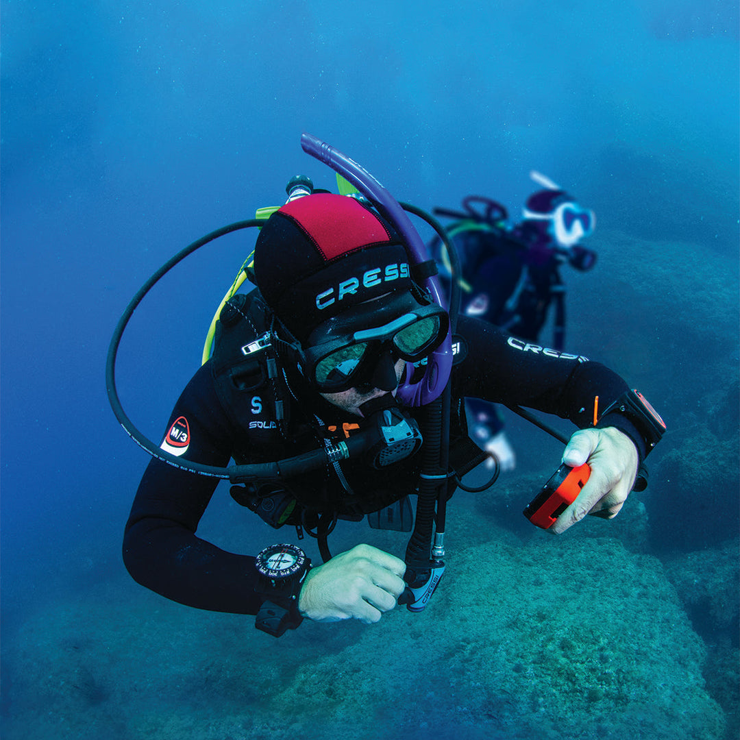 Diver underwater wearing a Cressi diving helmet and equipment.