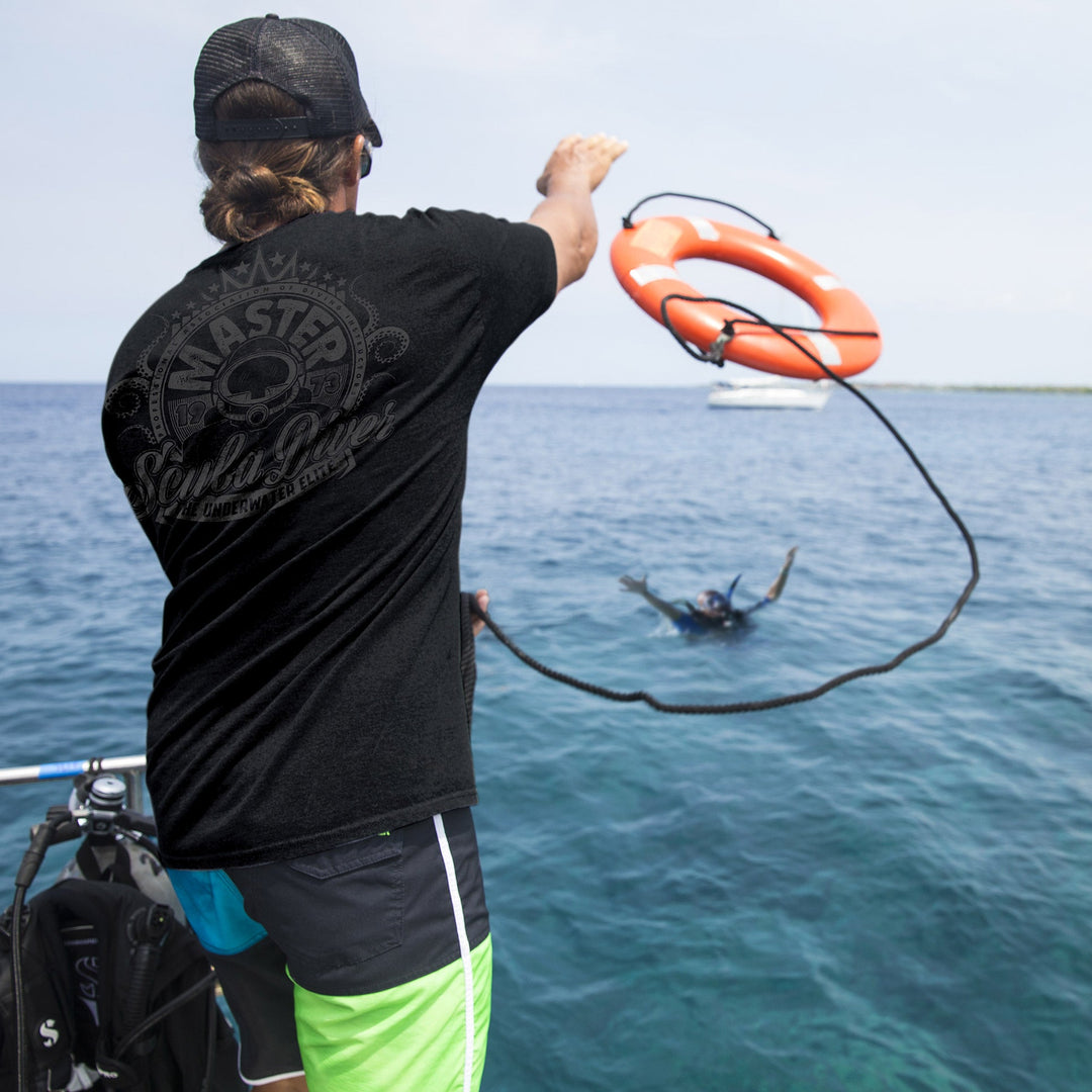 Person holding a life preserver over water with another person in the distance.